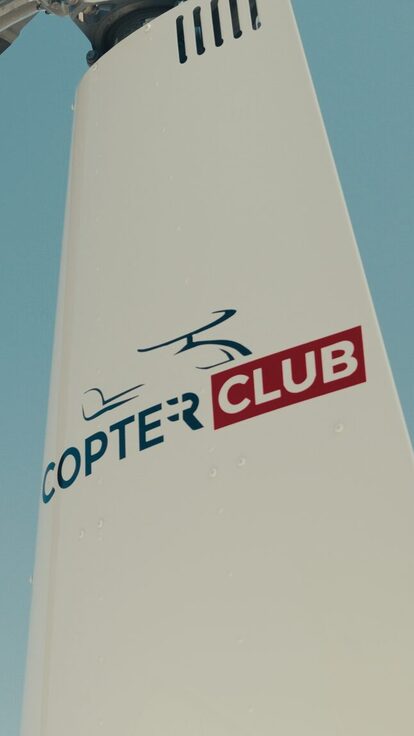Queue d'hélicoptère Copter Club sous ciel bleu clair.