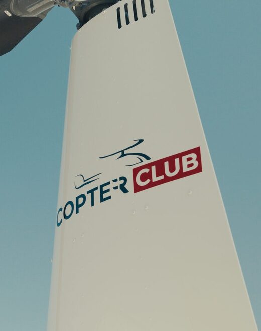 Queue d'hélicoptère Copter Club sous ciel bleu clair.