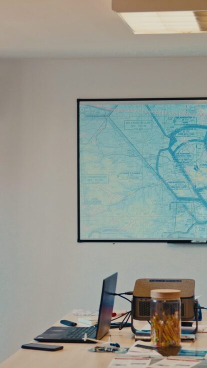 Un homme montre une carte en salle, avec bannière de l'école Copter Club visible.