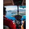 Deux pilotes survolent côte et collines en hélicoptère.