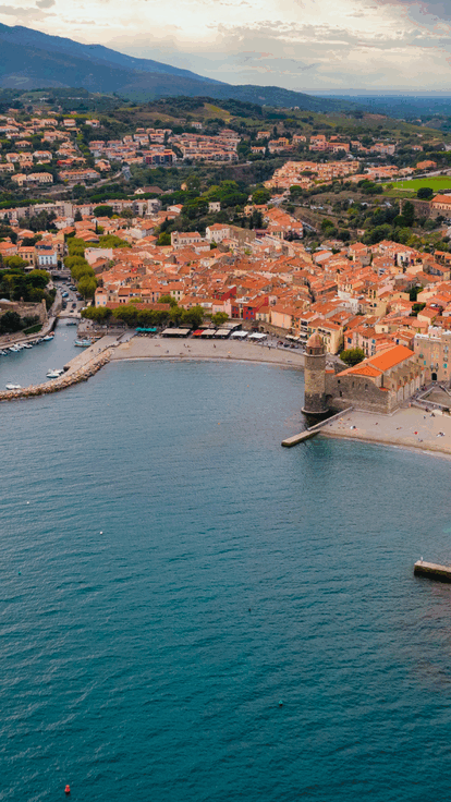 Vue aérienne d'une ville côtière, collines et mer.